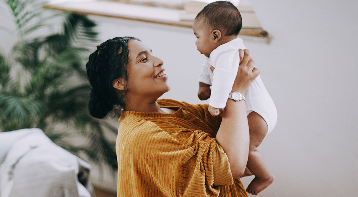 A Covered California member plays with her baby at home.