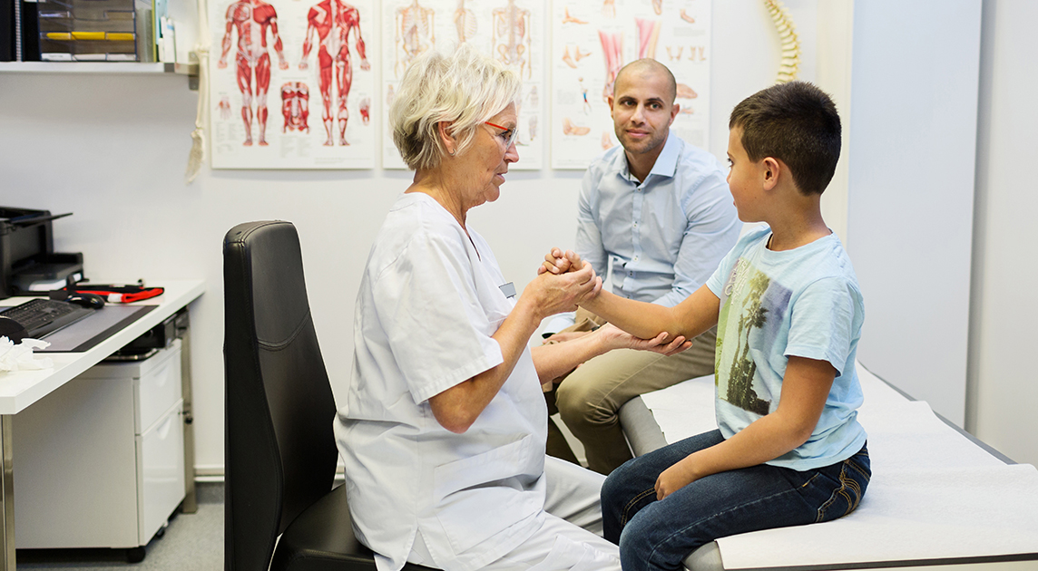 A health care worker checks a boy’s arm during a doctor’s visit.